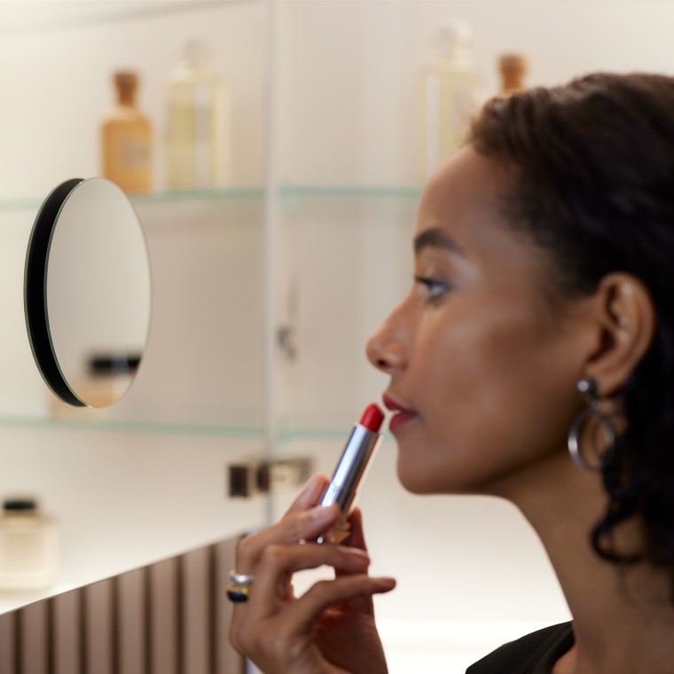 Ženska osoba se šminka u ogledalu